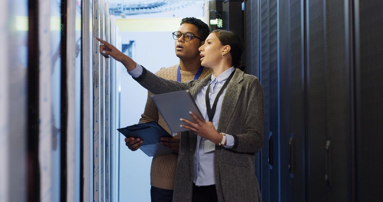 Two colleagues reviewing a server rack with a tablet