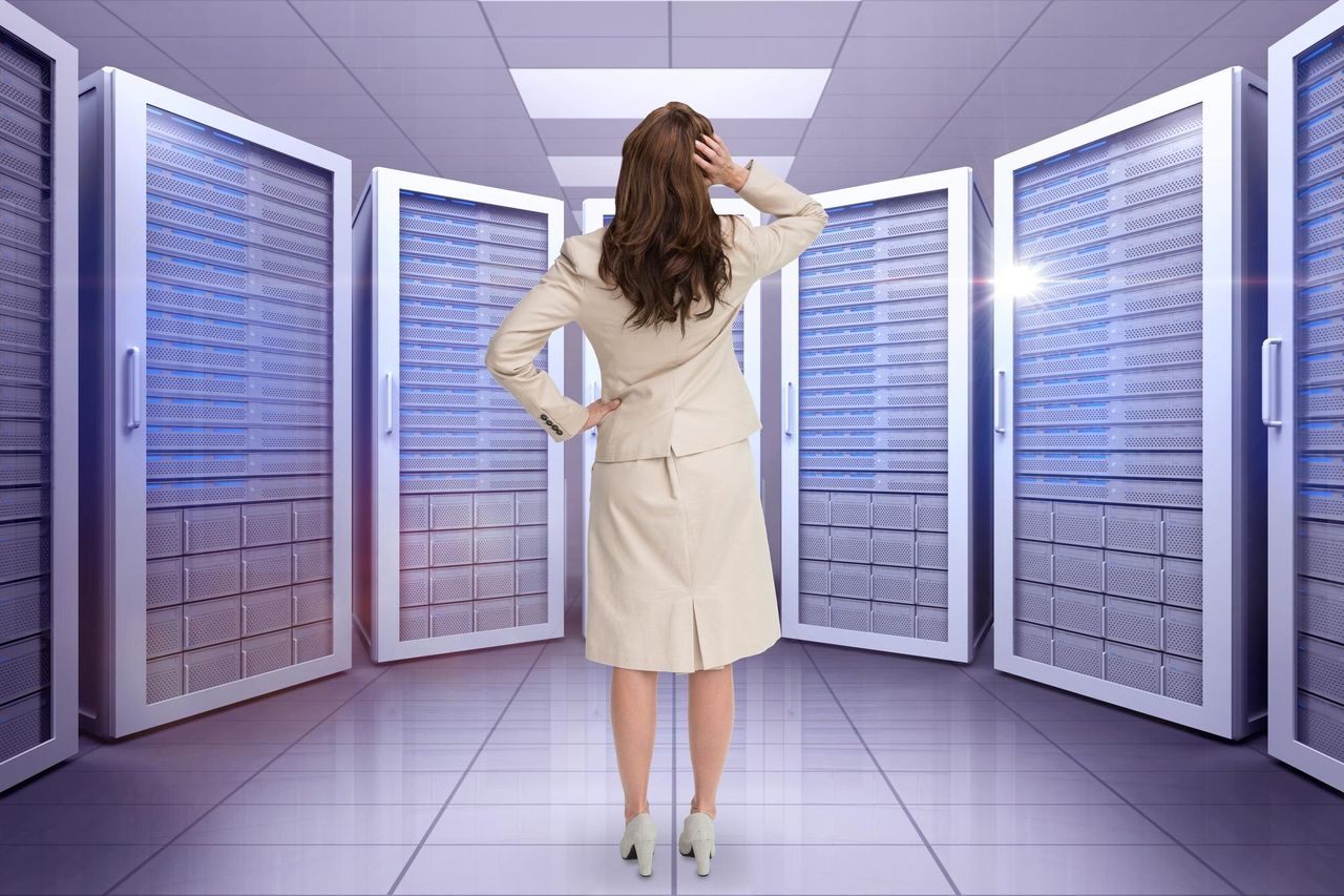 Woman standing between rows of server racks