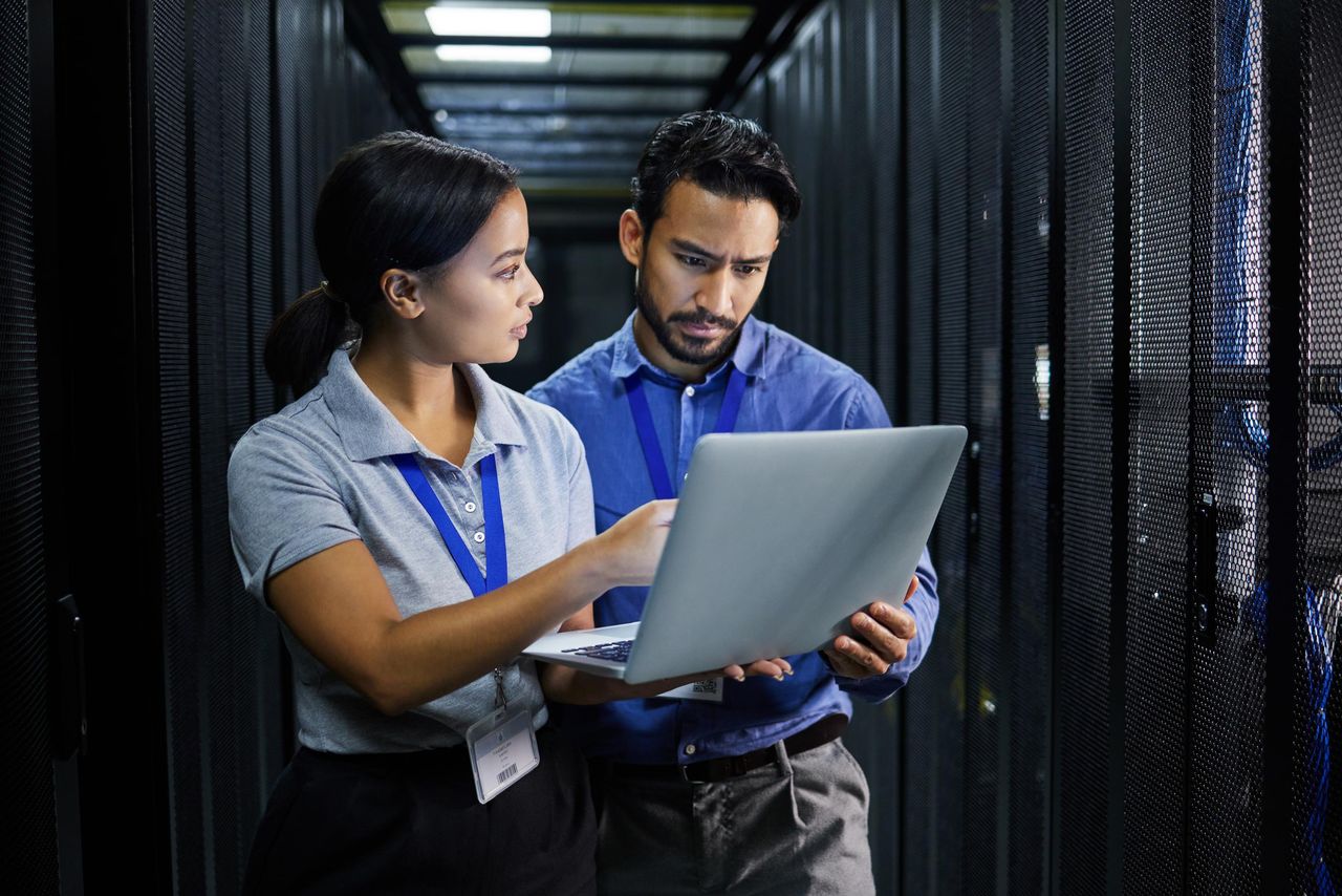 Engineers reviewing a laptop beside server racks